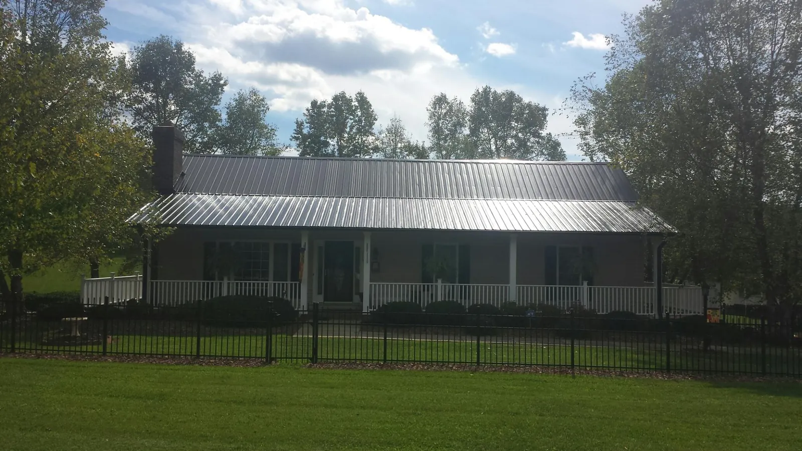 Gray metal roof on a brick ranch with a full width front porch — Gutter Guard Installation work by our crew in Paris
