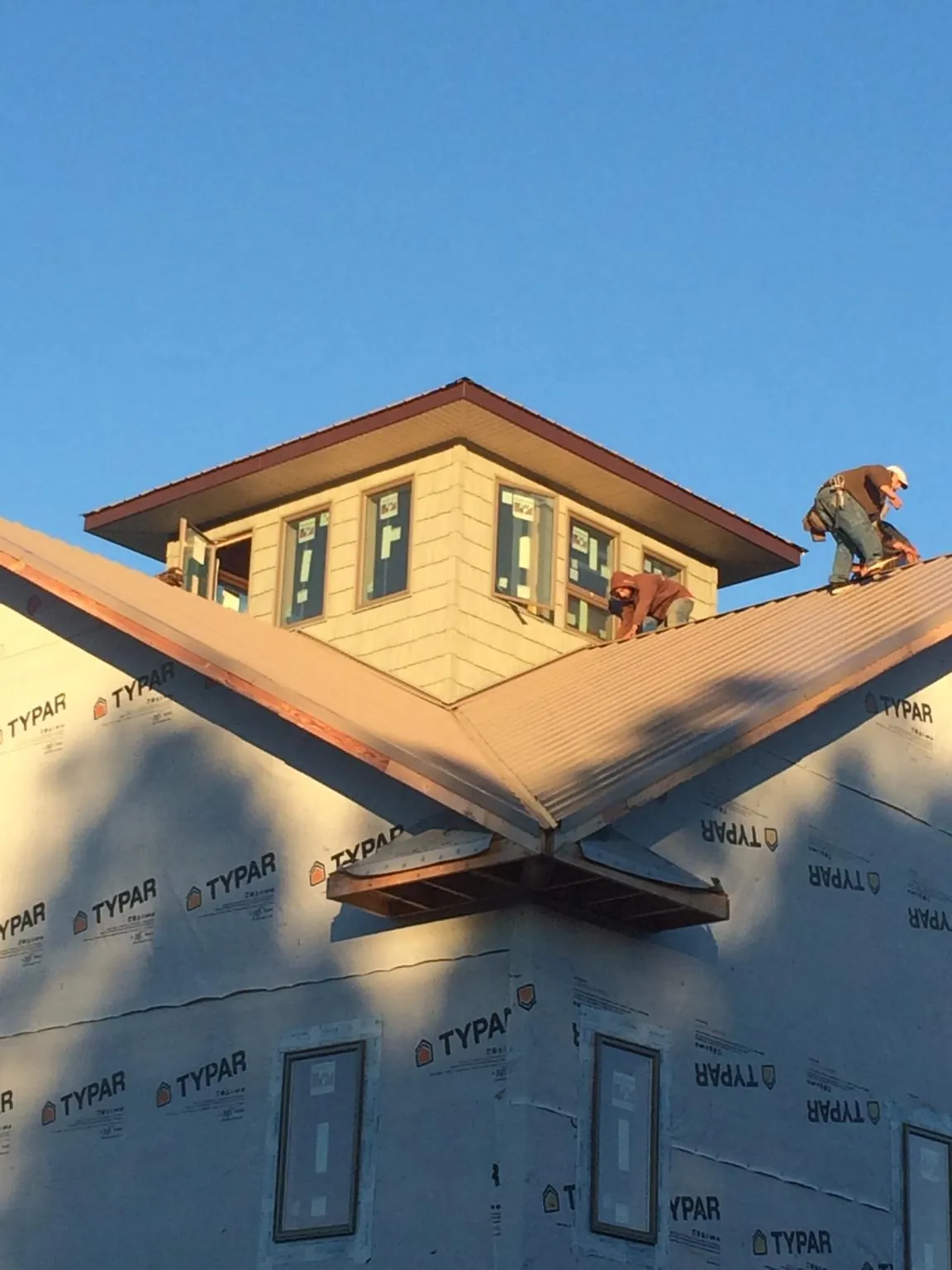 Roofers working around a rooftop cupola on a new metal roof at sunset — Roof Waterproofing in Paris by Roofing Brothers